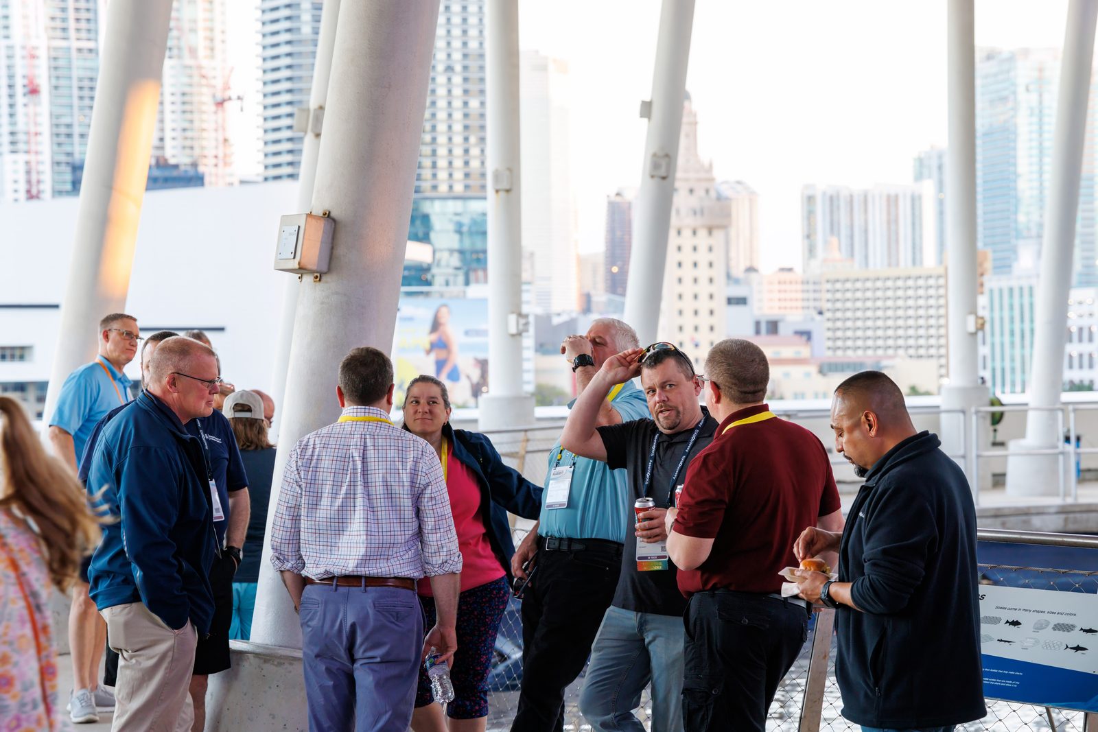 Attendees with conference badges talking on the terrace of the Frost Science Museum with downtown Miami towers behind them