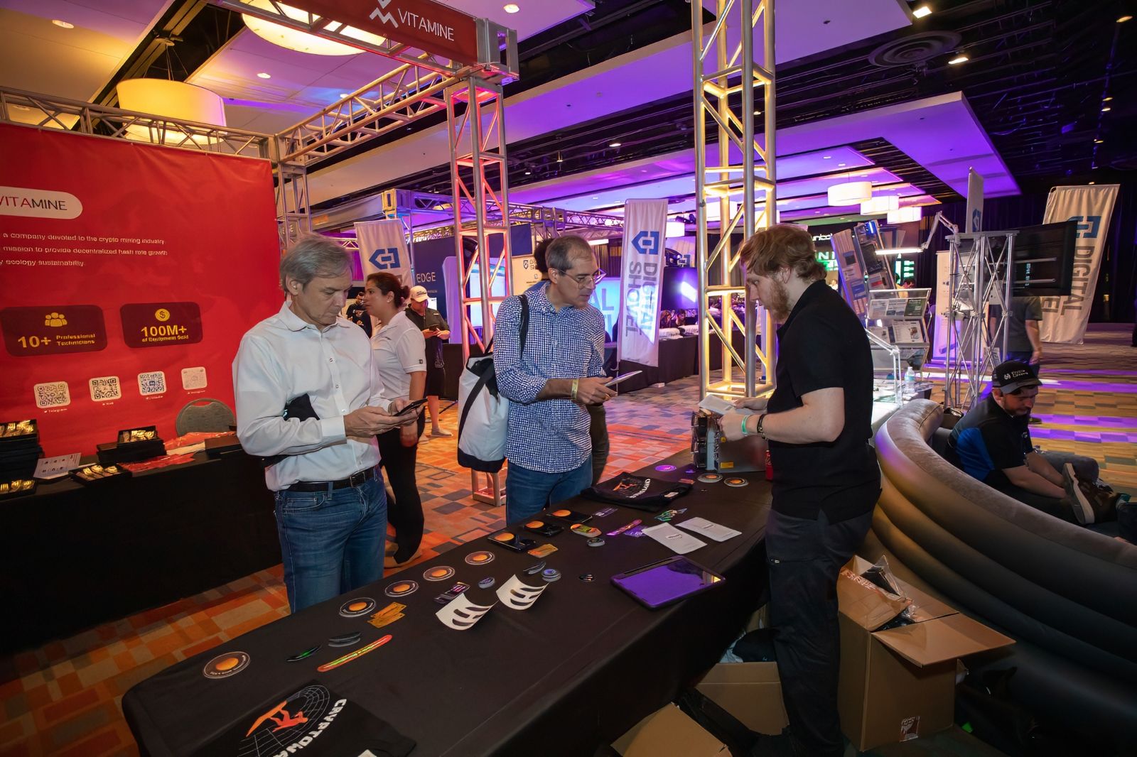 Visitors at a red-walled booth on the show floor