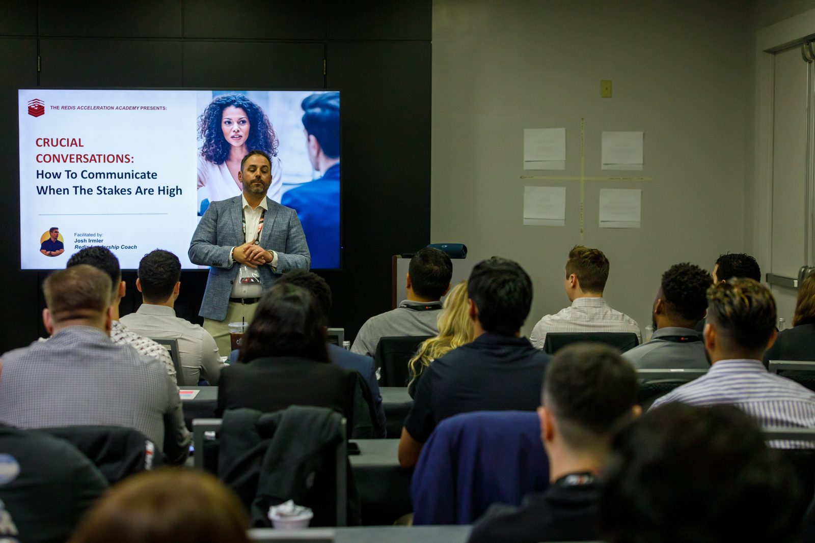 Presenter speaking beside a large slide to a full breakout room