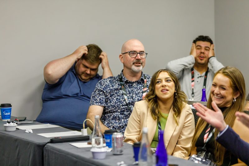 Attendees laughing together at a table during a breakout session