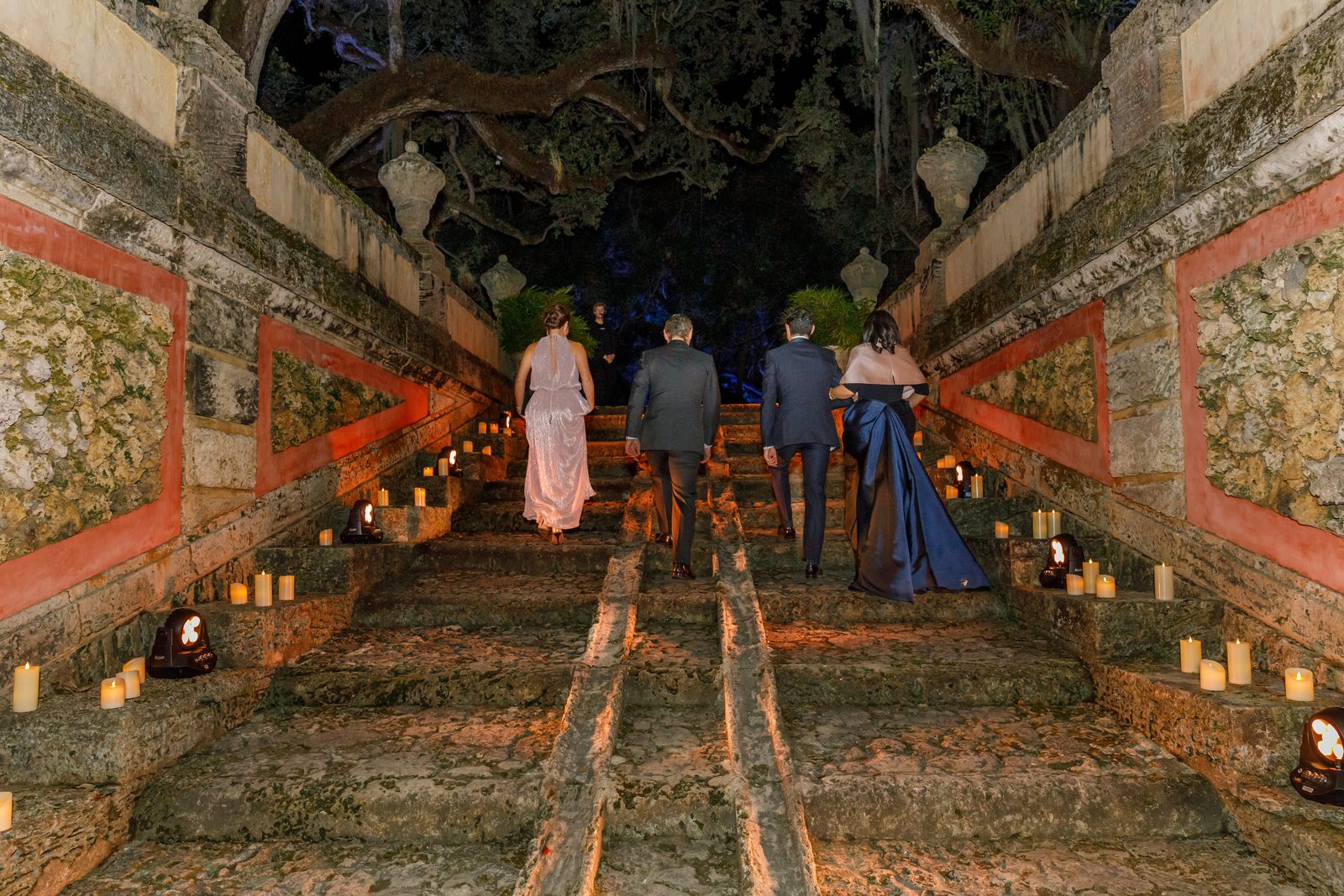 Guests in evening dress climbing candlelit garden steps at Vizcaya Museum and Gardens