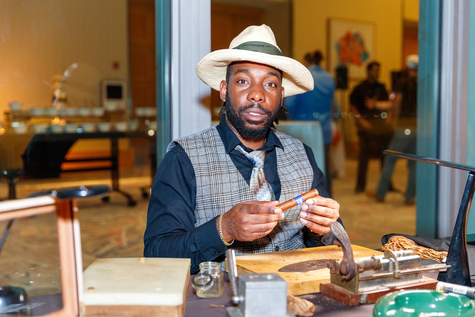 Cigar roller in a Panama hat hand-rolling cigars for guests at a conference reception in Miami