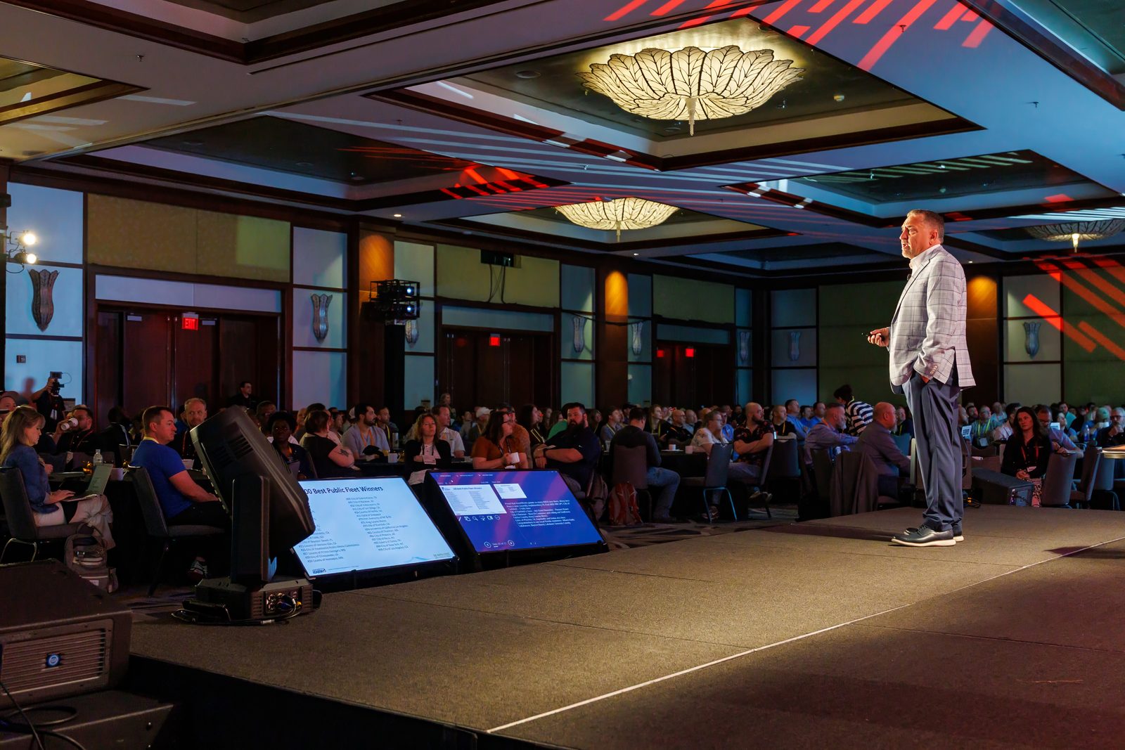 Keynote speaker on stage facing a packed hotel ballroom