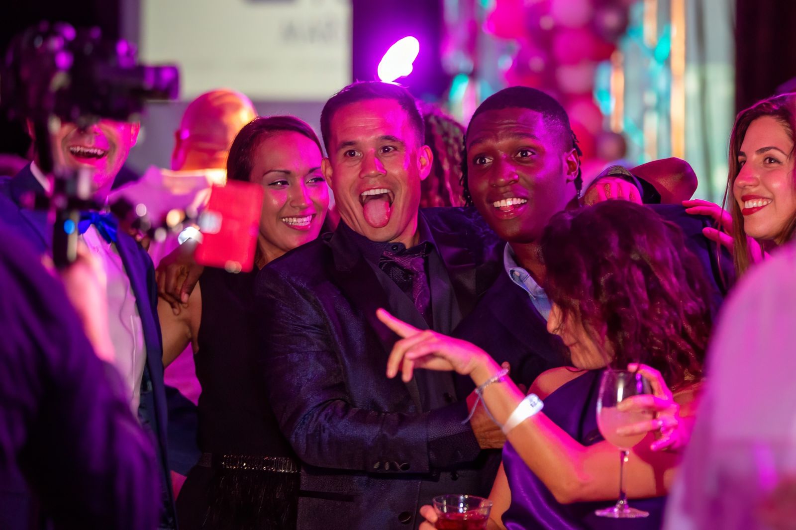 Guests celebrating under purple and pink light at an evening party