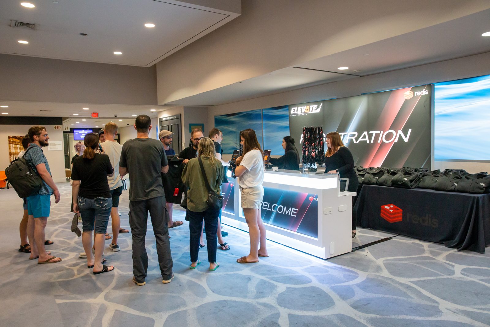 Attendees crowding a lit registration desk as check-in opens