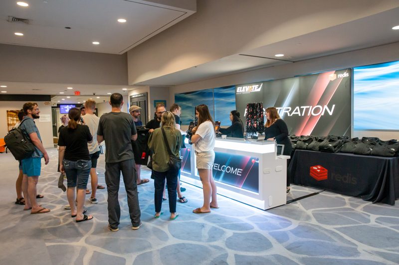 Attendees crowding a lit registration desk as check-in opens