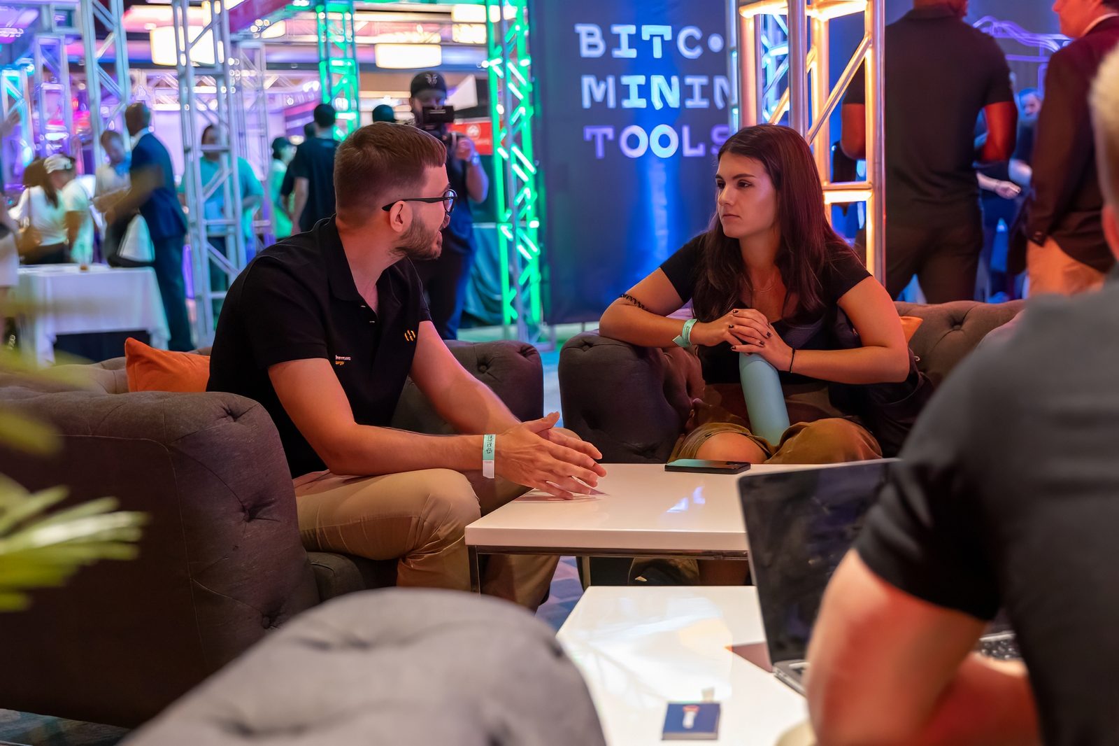 Attendees talking in a lounge area on a lit trade show floor