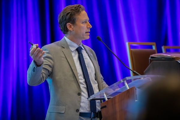 Speaker at a clear podium with purple stage lighting
